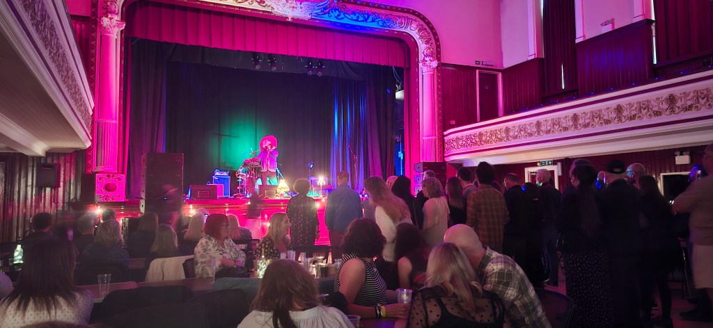 A mask wearing Pictish Trail on stage at the Dobbie Hall 